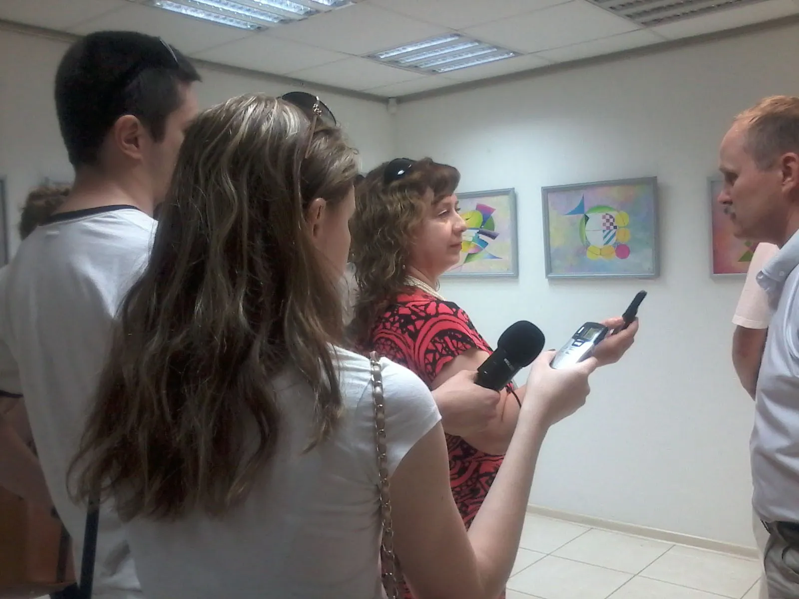 Visitors and a journalist with a microphone at the opening of the exhibition in Zaporizhzhia