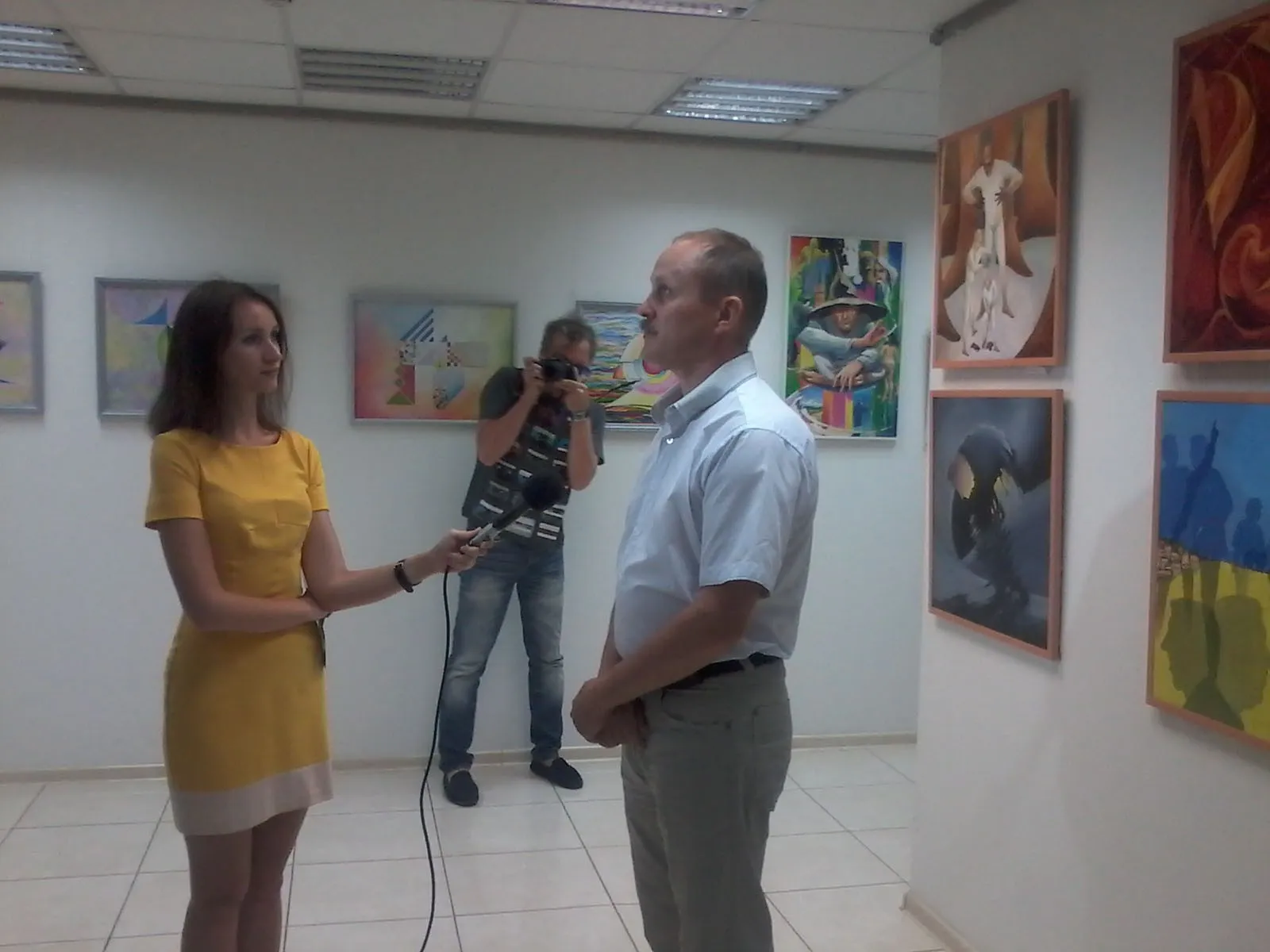 The artist being interviewed for television in front of his paintings