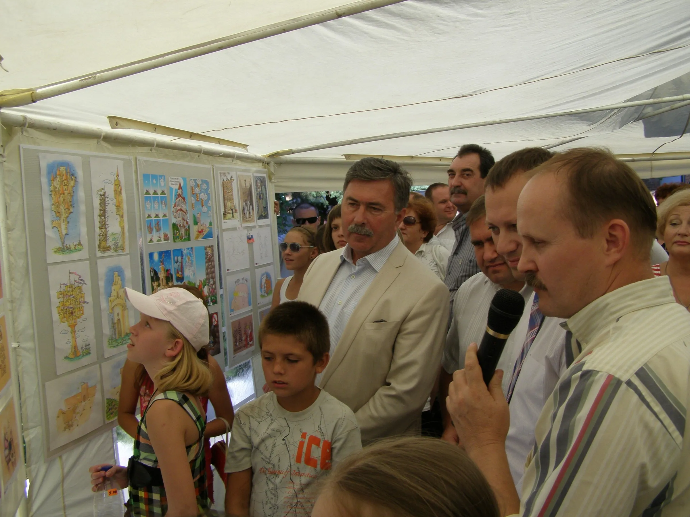 Children and visitors looking at cartoons pinned up along the walls of the competition marquee